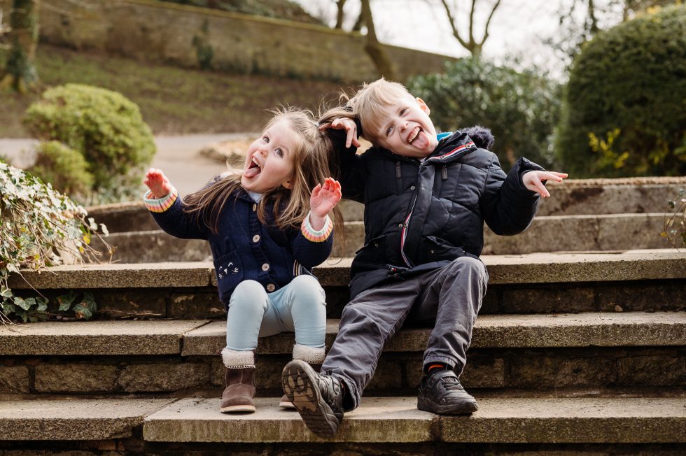 Lancashire family photographer at Clitheroe Castle with a little boy and a little girl sat on the stone steps pulling faces