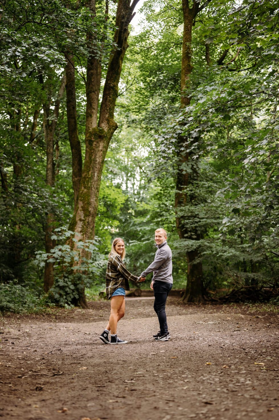 Cute couple on their pre wedding shoot in the woodland and looking back at the camera