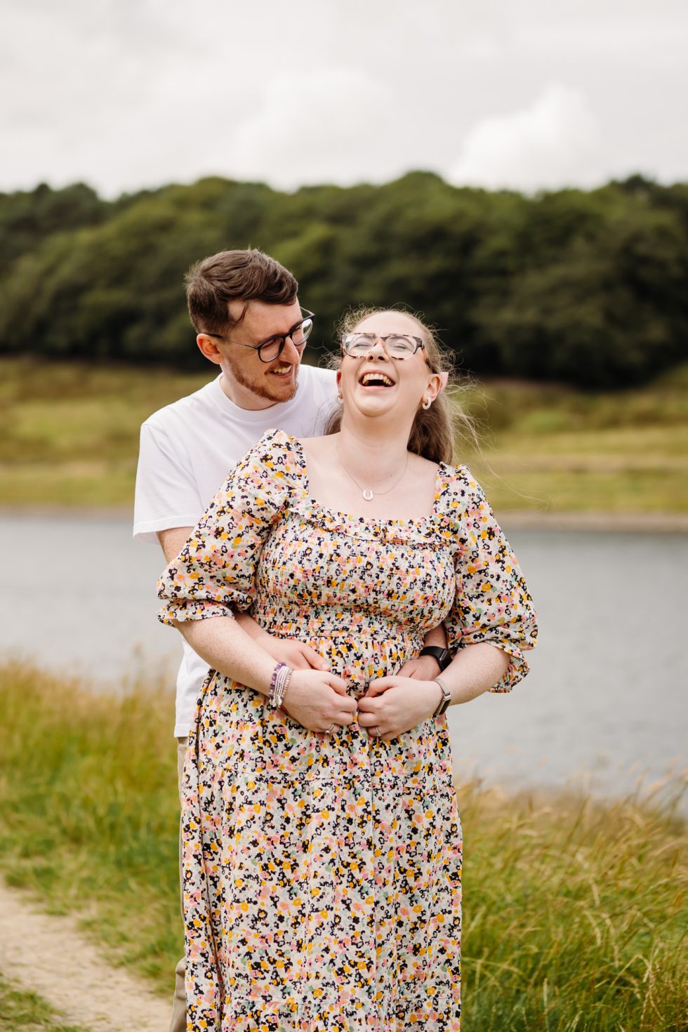 Groom to be is stood behind his future bride and she is laughing