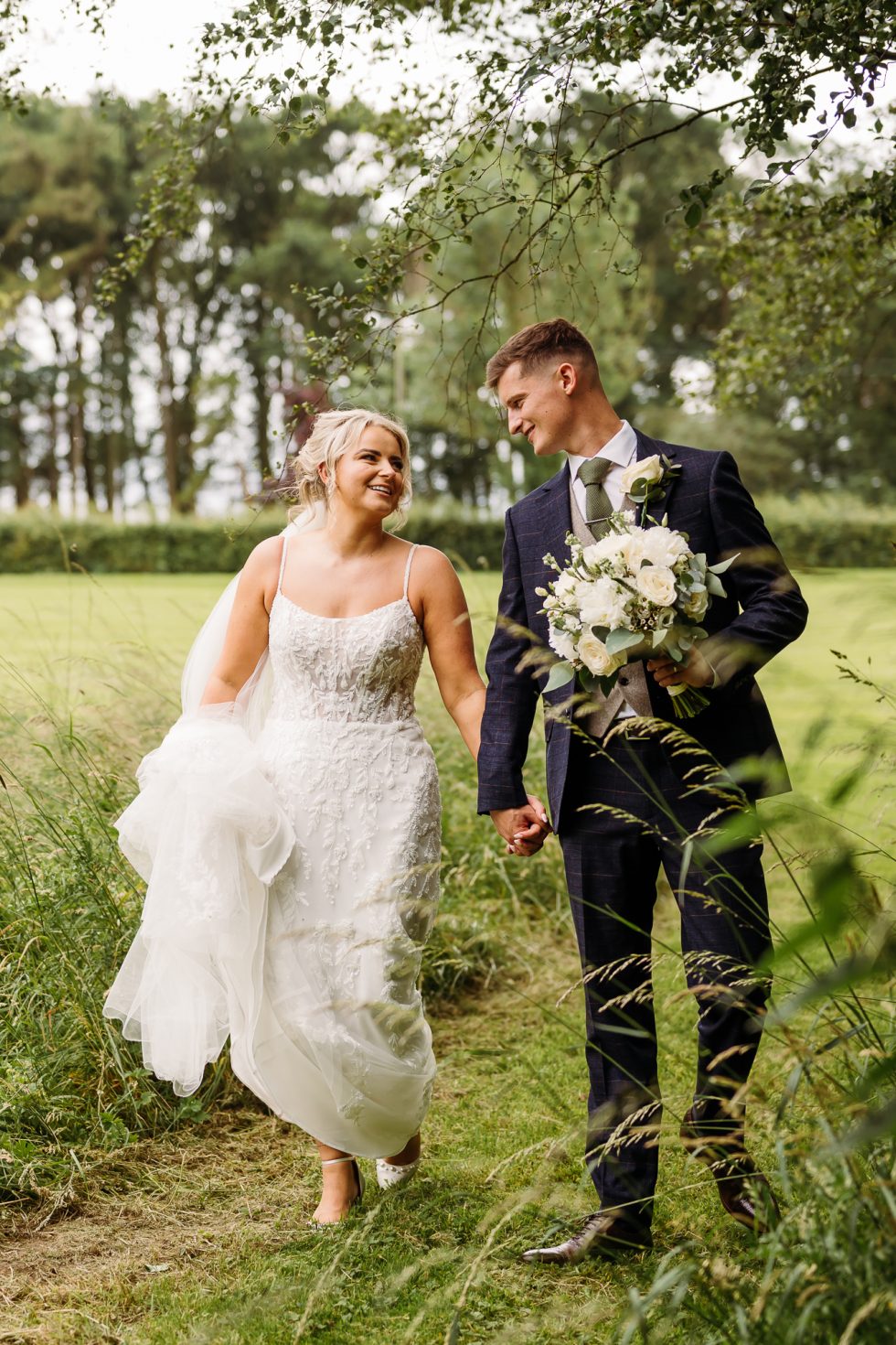 Bride and groom walking through the gardens during their Summer Wedding at Stirk House