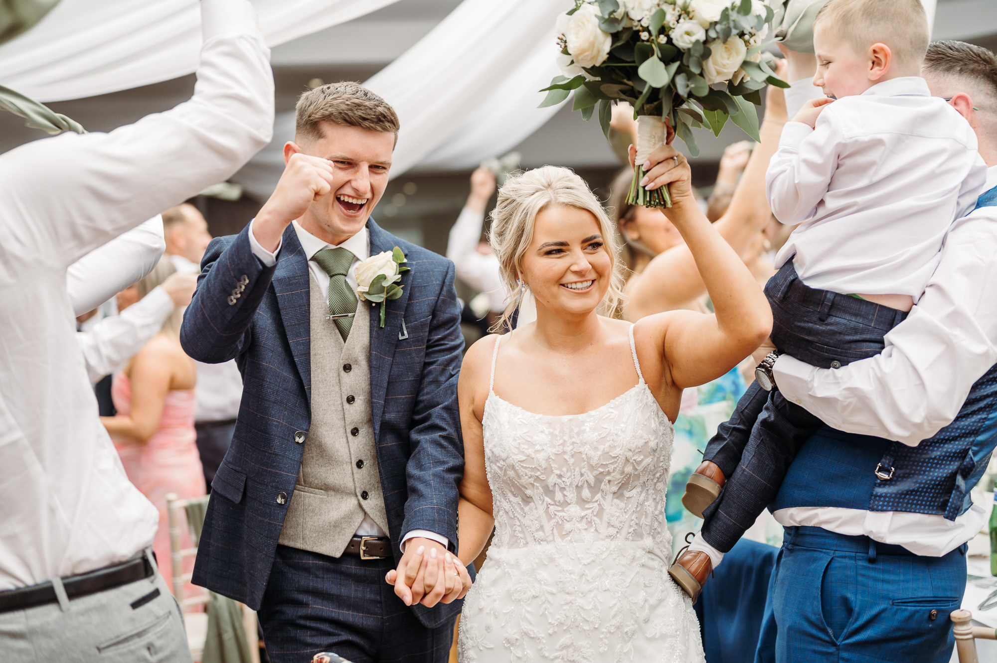 Bride and groom dancing in for their wedding breakfast. Guests are clapping and cheering.