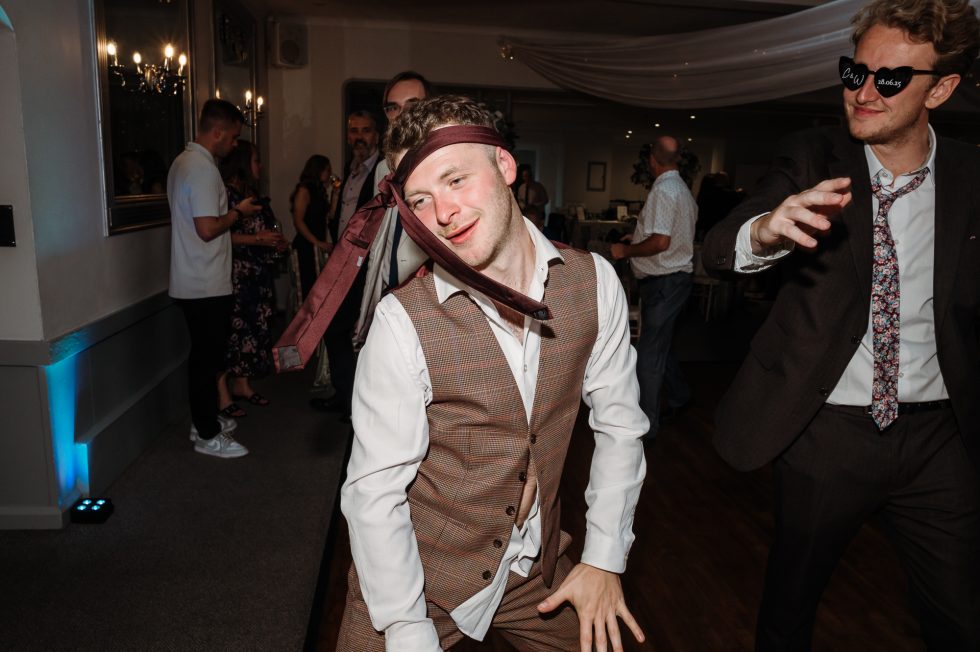 Male wedding guest dancing with a tie around his head at Stirk House