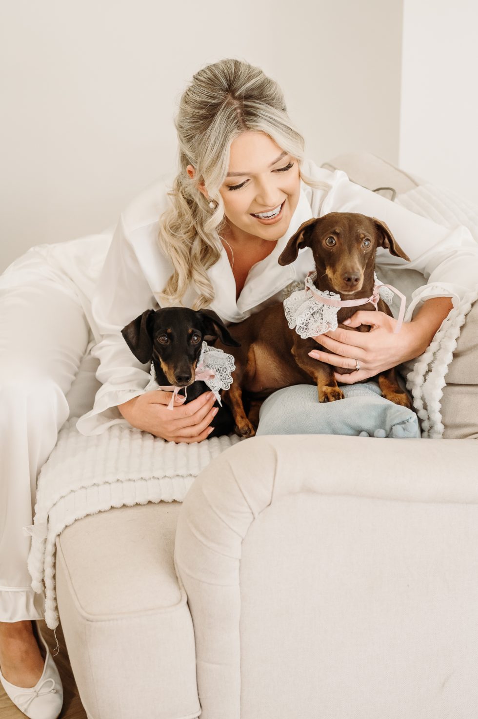 Bride cuddling her two mini dachshunds on the morning of her wedding