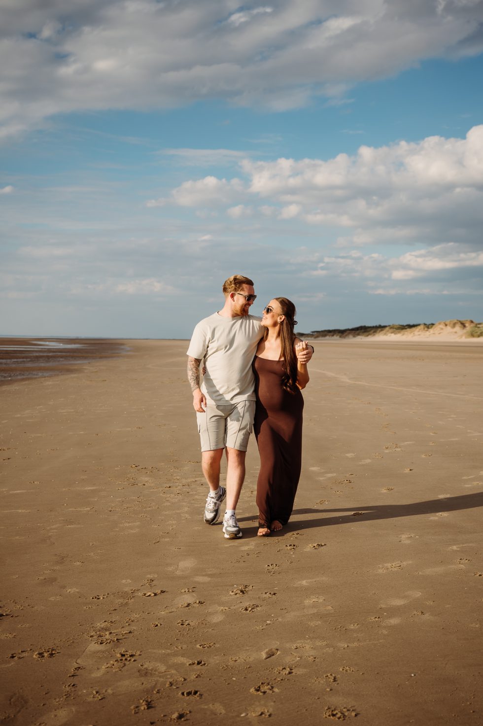Lancashire Beach Proposal Shoot. Newly engaged couple walking along Formby beach