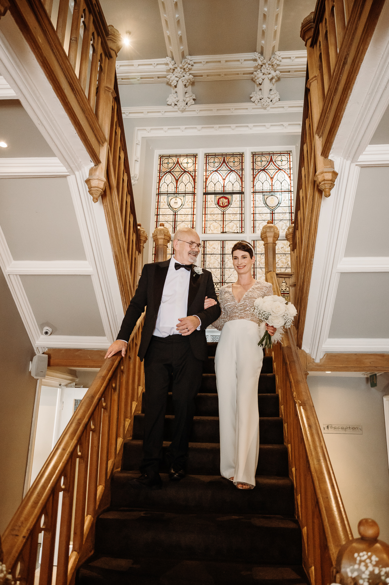 Father of the bride helping the bride down the stairs at Didsbury House Hotel