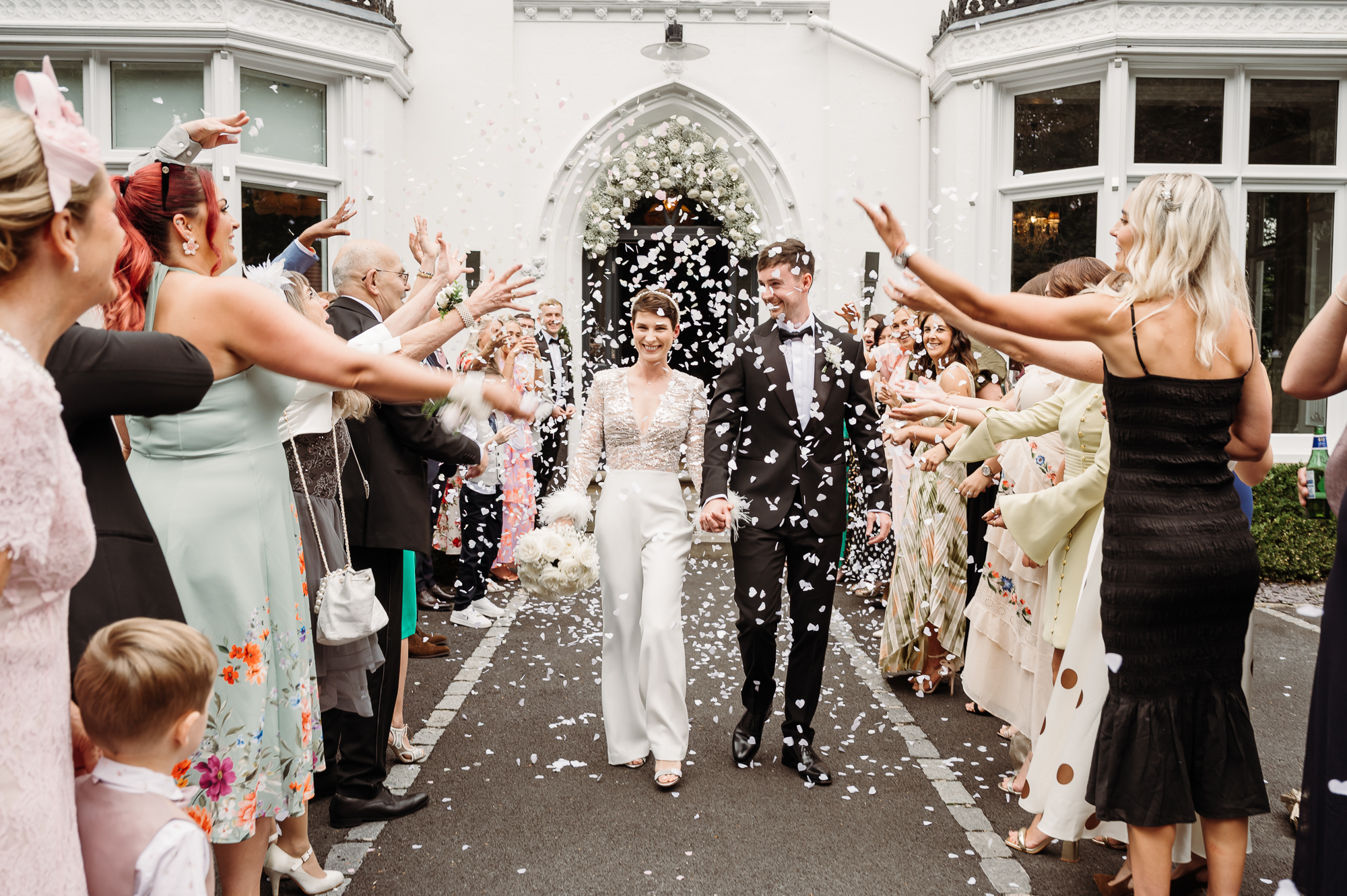 Bride and groom walking through the confetti aisle by Didsbury House wedding Photographer