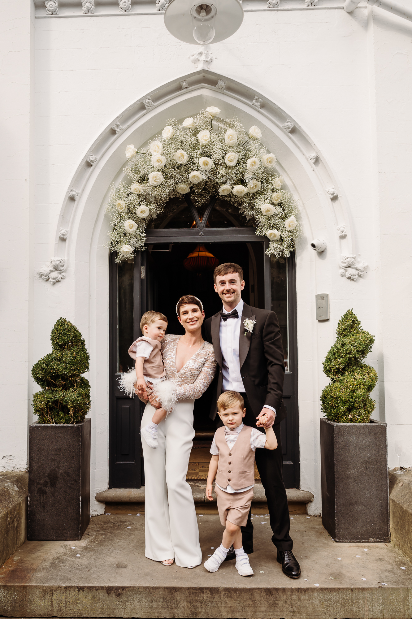 Family shot of bride, groom and their children on the steps at Didsbury House Hotel