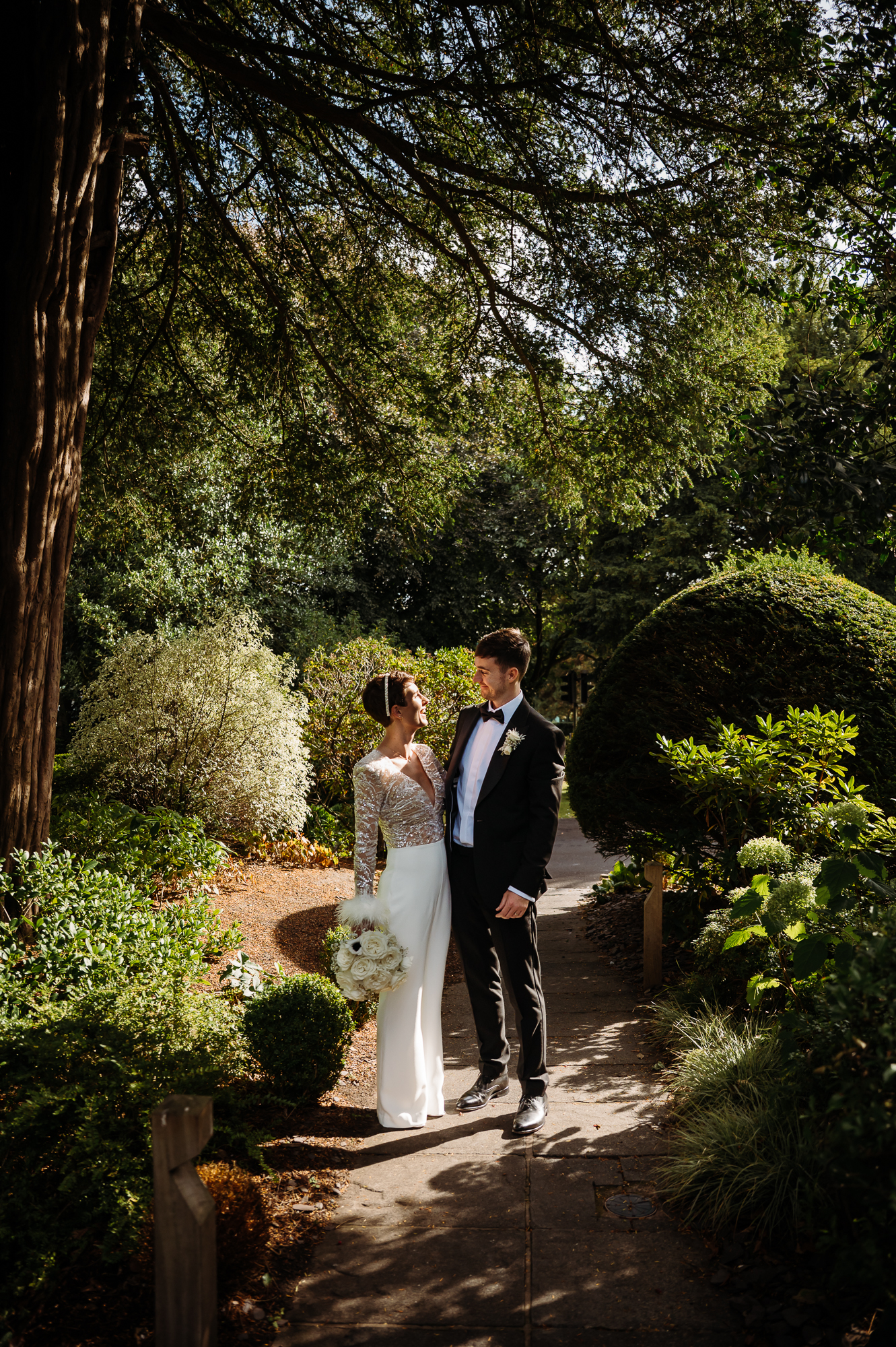Bride and groom stood in the shade of the garden by Didsbury House wedding Photographer