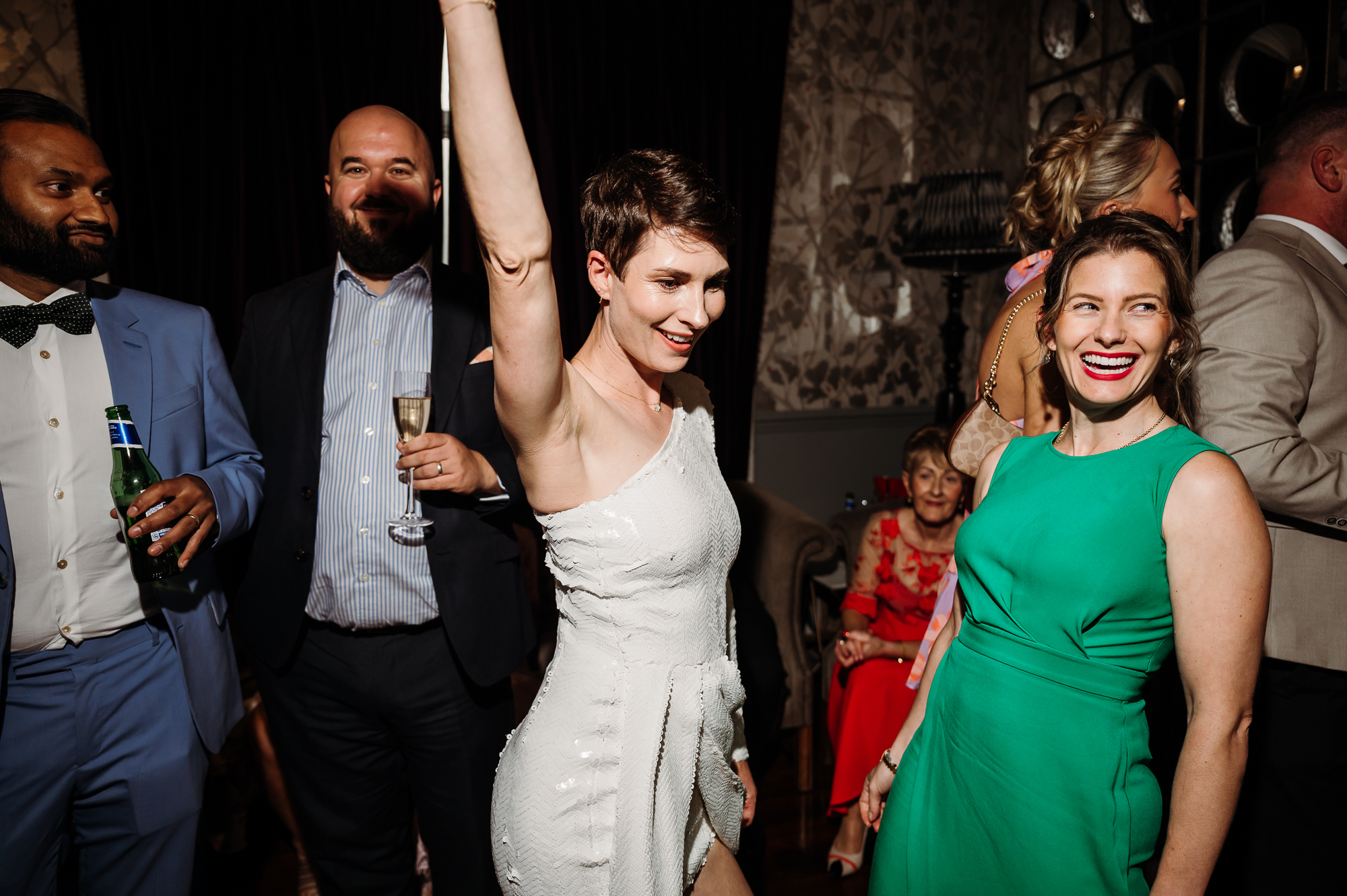 Bride dancing with her hand in the air by Didsbury House wedding Photographer