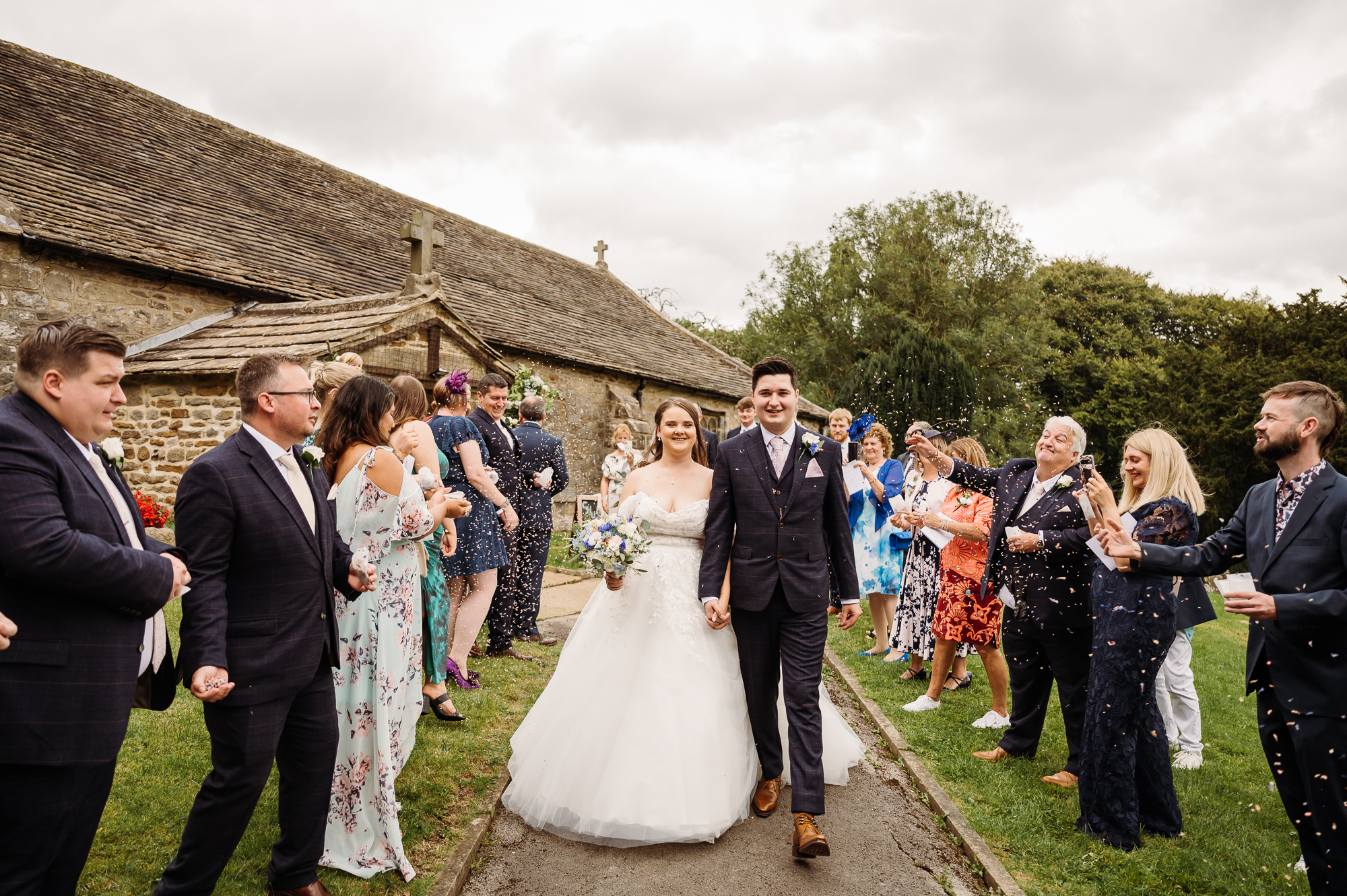 Confetti walking shot of the bride and groom in front of the church
