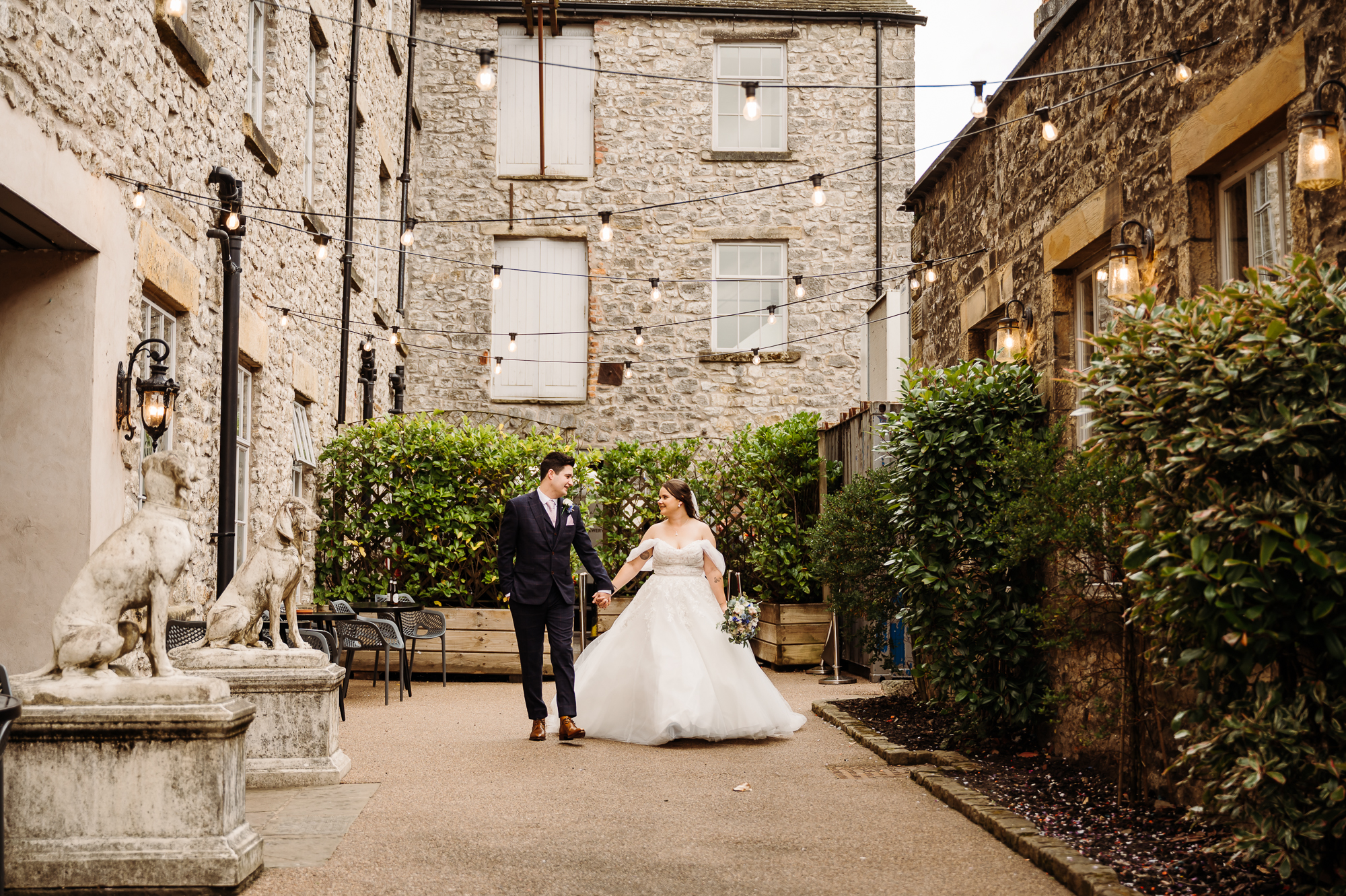 Bride and groom walking in the courtyard by Holmes Mill Wedding Photographer