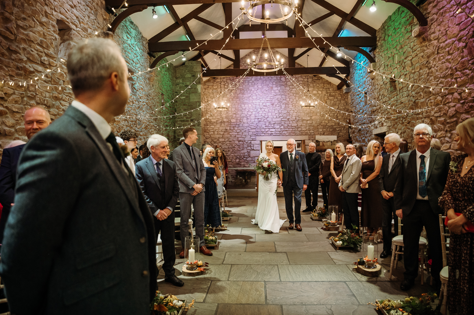 Father of the bride is walking his beautiful daughter down the aisle at Browsholme and the groom is watching her.