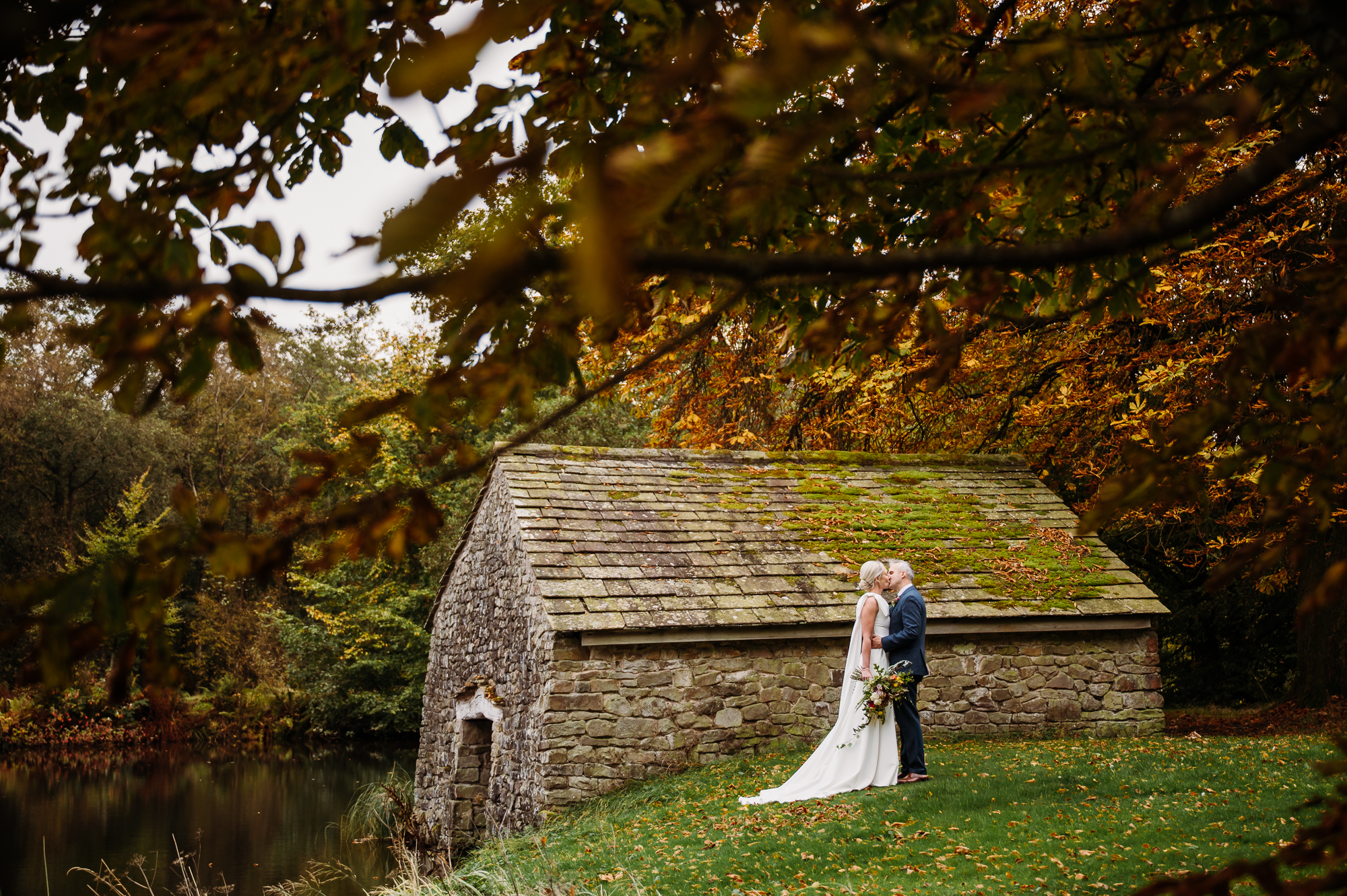 Bride and groom are hugging by the boat house by Browsholme Hall Wedding Photographer