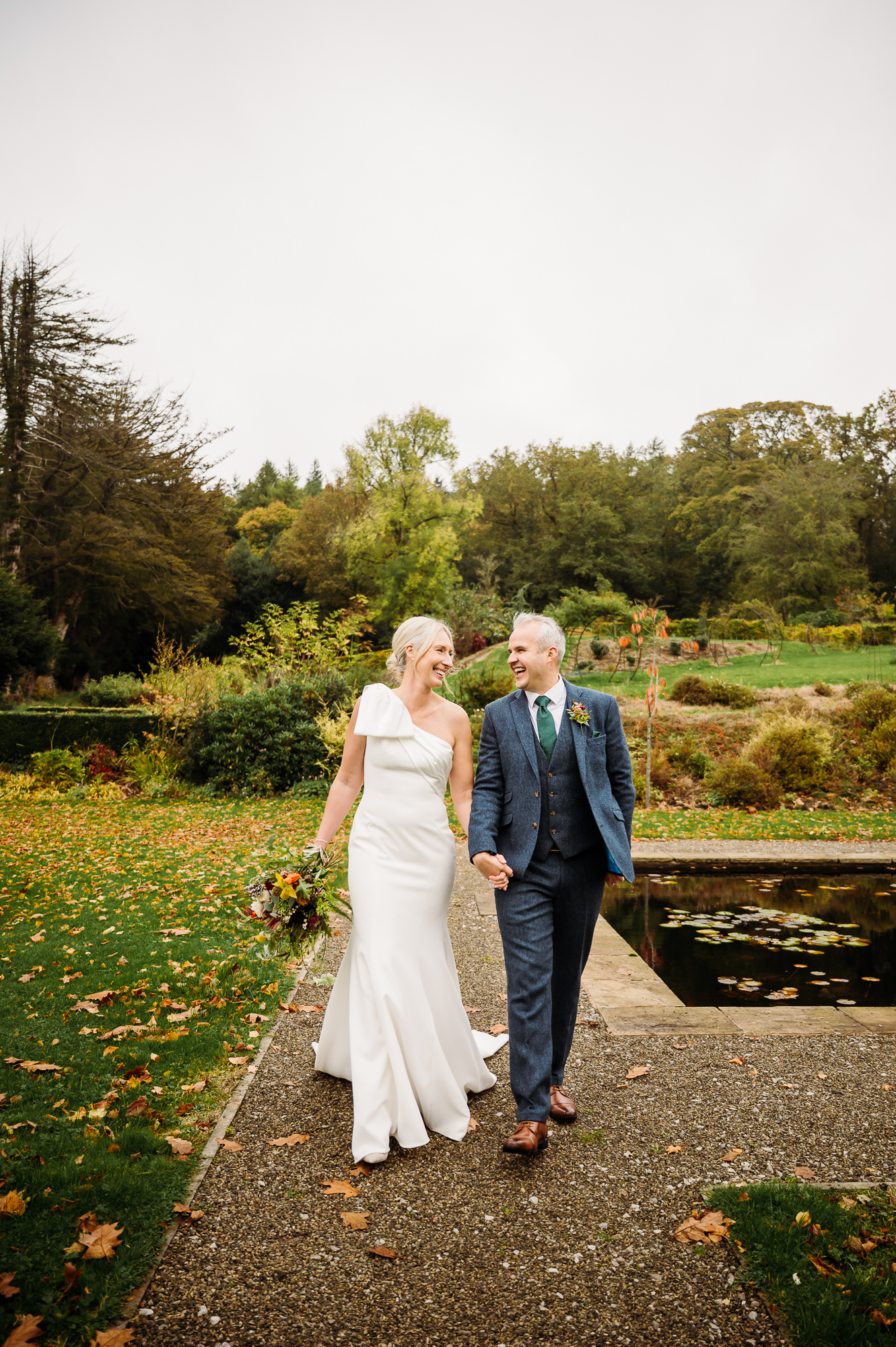 Bride and groom are walking hand in hand by the lily pond by Browsholme Hall Wedding Photographer