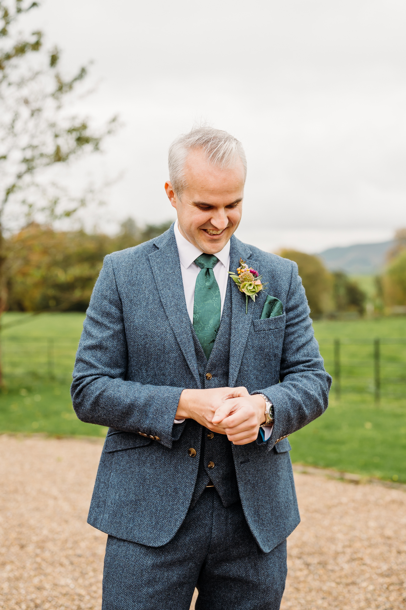The groom is adjusting his cuffs on his shirt before his wedding.