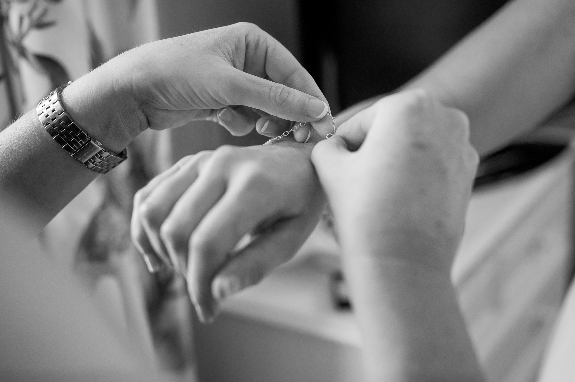 Detail shot of a bridesmaid helping the bride put on her bracelet by Browsholme Hall Wedding Photographer