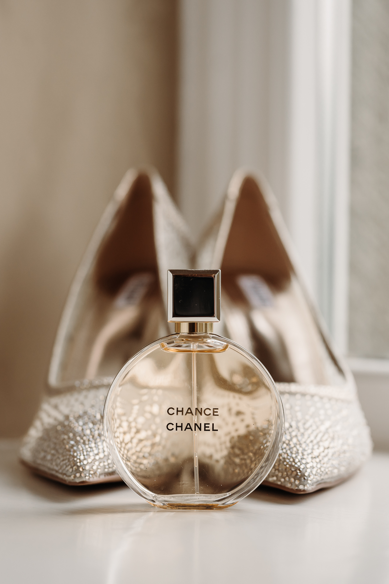 Detail shot of brides wedding shoes and Chanel perfume