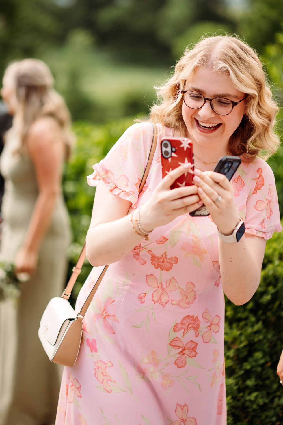 Cute shot of a female wedding guest wearing glasses and taking a photo with her phone
