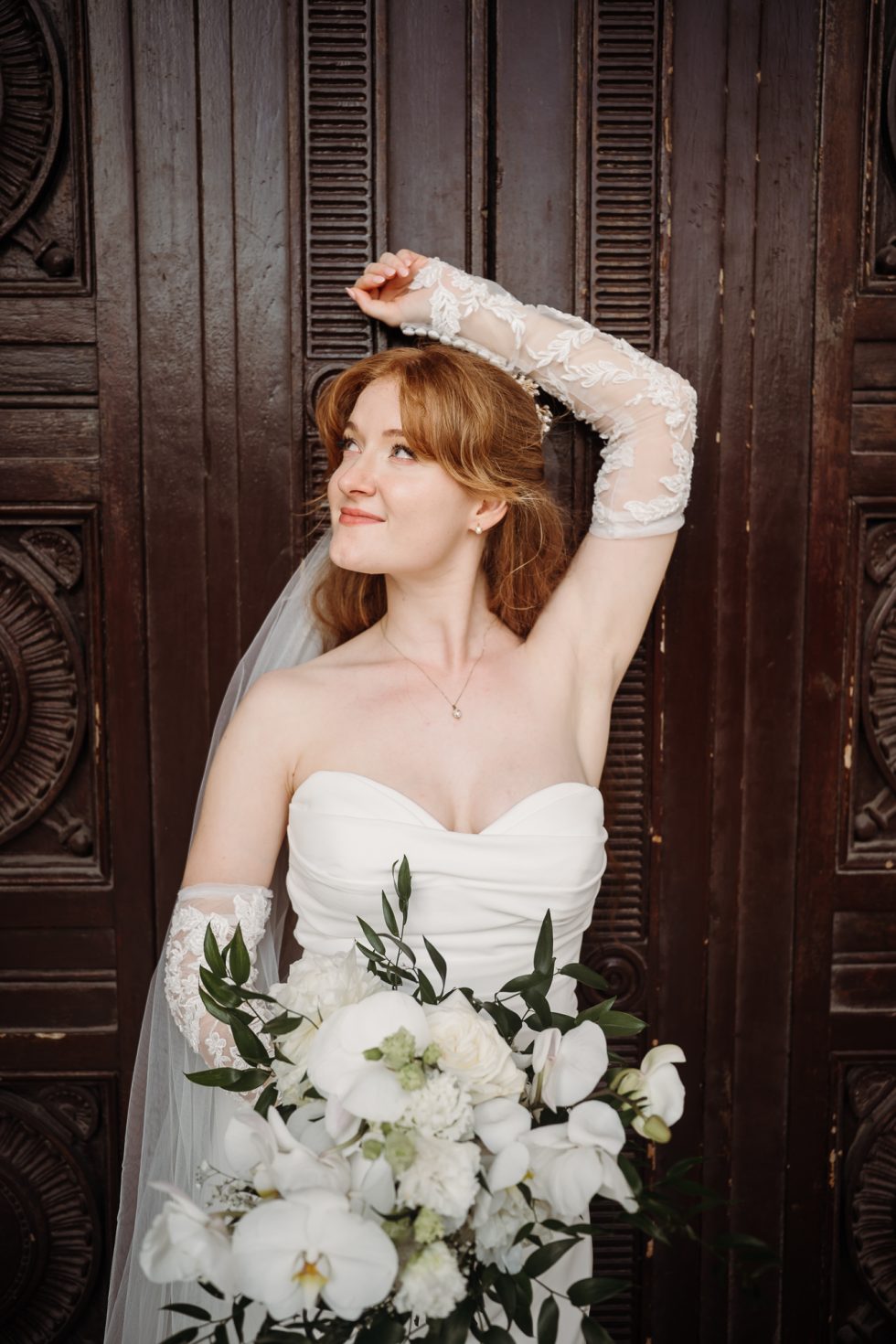 Bride with her arm over her head in front of a door
