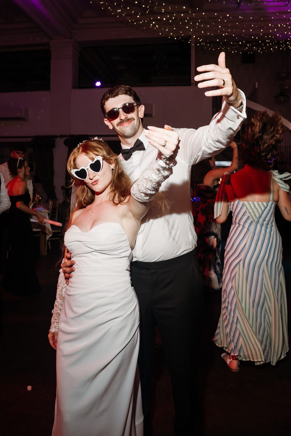 Bride and groom on the dance floor with sun glasses on and showing off their wedding rings by Lancashire wedding photographer