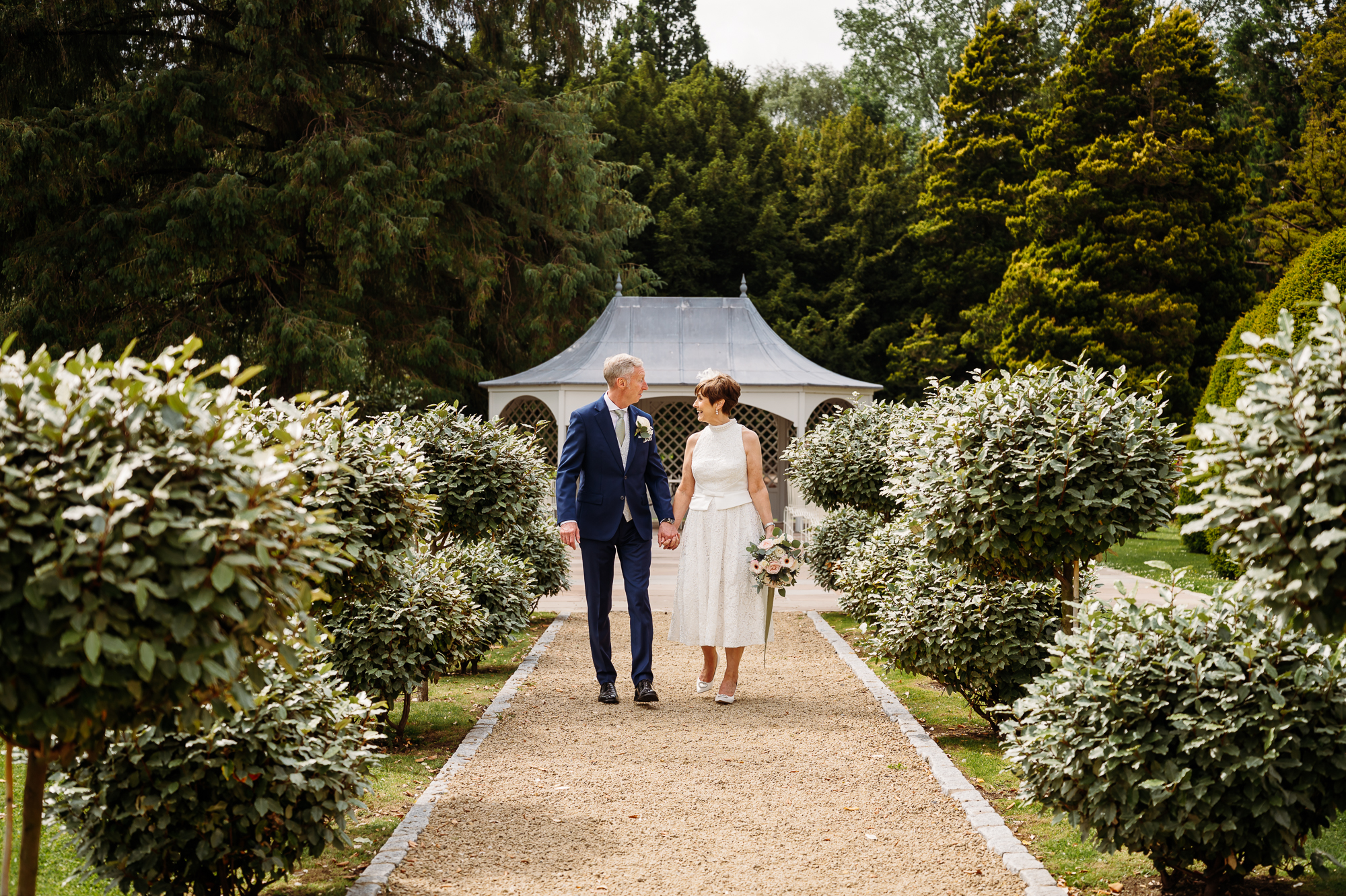 Mature bride and groom walking through the grounds by Wennington Hall Wedding Photographer