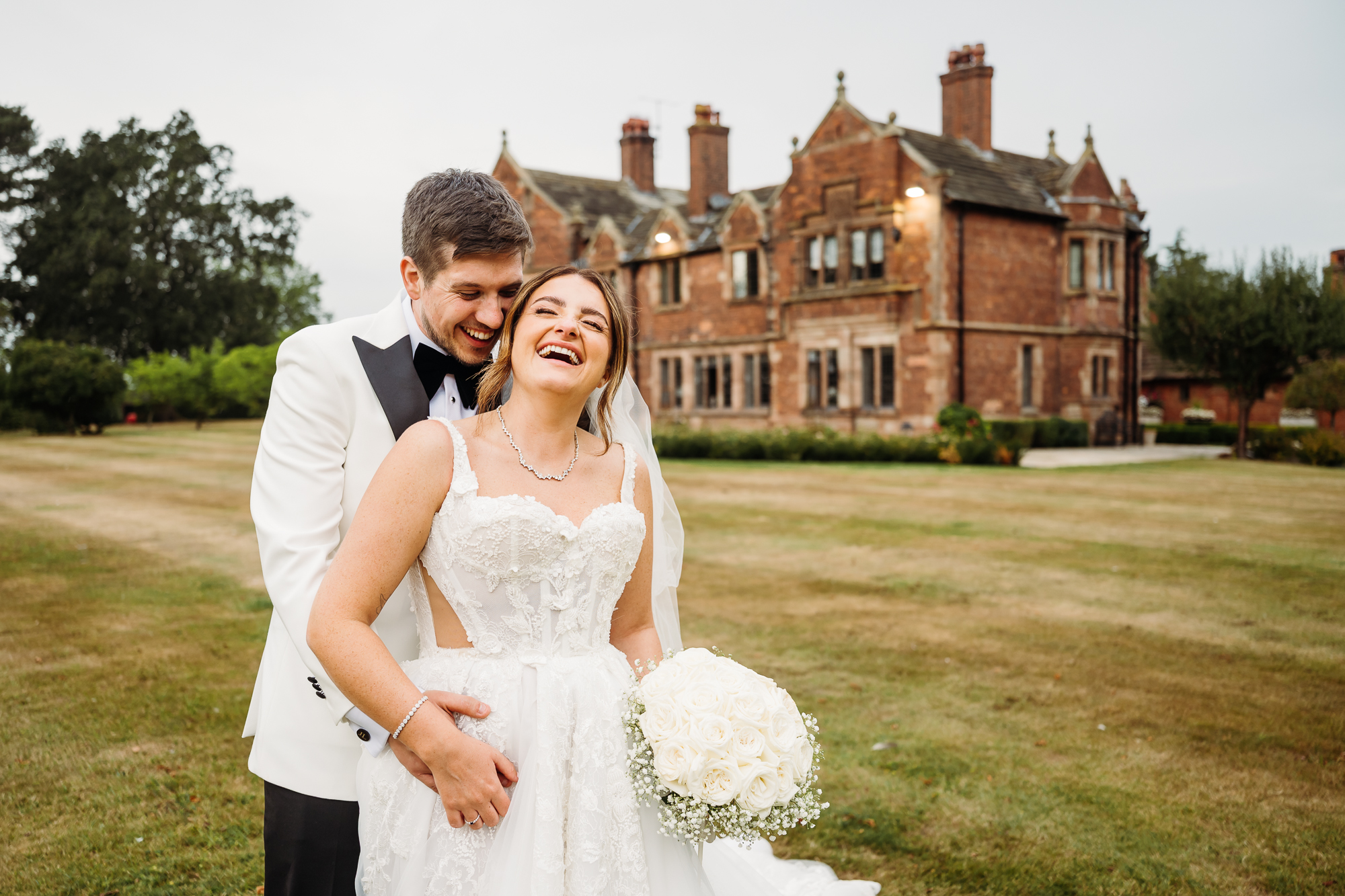 Gorgeous bride and groom. They are laughing with their backs towards colshaw hall
